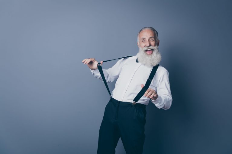 Portrait of his he nice attractive crazy cheerful cheery funny funky gray-haired man pulling suspenders clothes clothing having fun isolated over dark grey pastel color background
