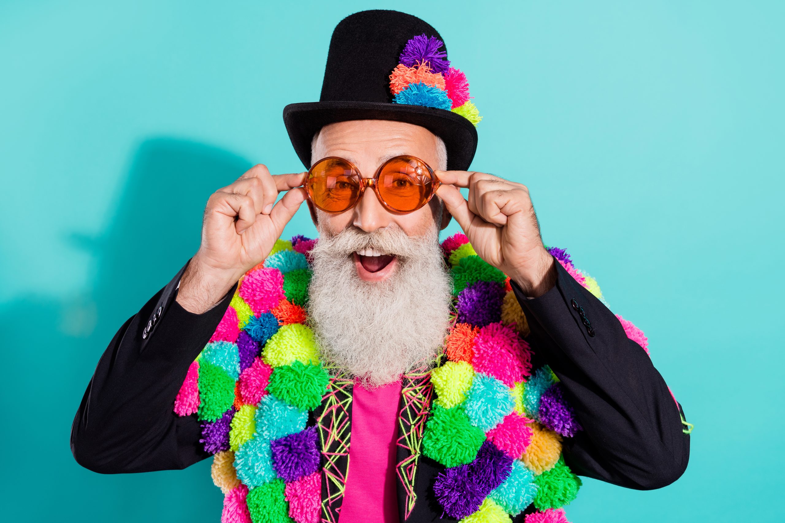 Photo of dreamy excited mature showman dressed creative pom-pom jacket arms eyewear isolated turquoise color background